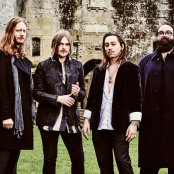 4 members of the band Mirador standing outside in front of an old building.